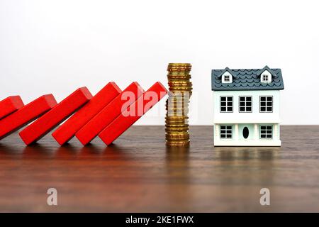 Domino-Effekt schützt Modellhaus mit Stapel von Münzen Stockfoto