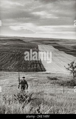 Landschaft mit einem Hochland-Wildjäger, der eine Schrotflinte trägt, während er im ländlichen Morton County, North Dakota, nach Vögeln jagt Stockfoto