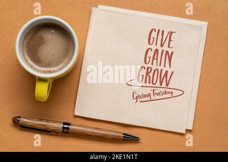 Geben, gewinnen und wachsen - Dienstags geben, geschäftliches und persönliches Entwicklungskonzept - Handschrift auf Serviette mit einer Tasse Kaffee Stockfoto