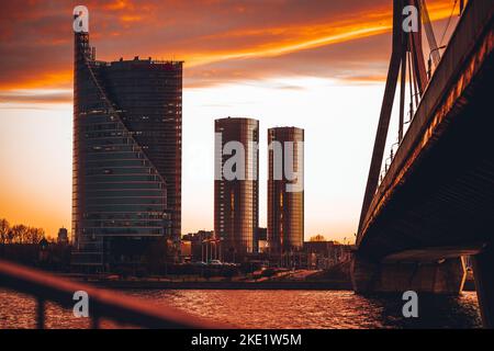 Eine szenische Aufnahme von der Vansu-Brücke, drei modernen Gebäuden in Riga bei Sonnenuntergang Stockfoto