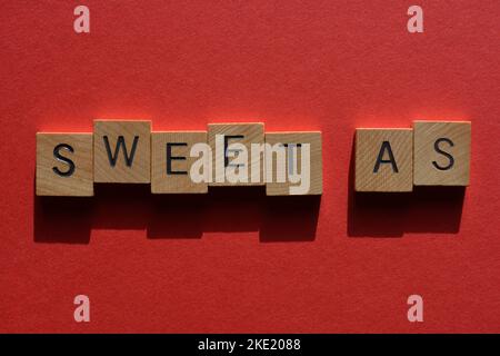 Sweet as, australischer Slang für ehrfürchtig oder gut in hölzernen Buchstaben isoliert auf rotem Hintergrund Stockfoto