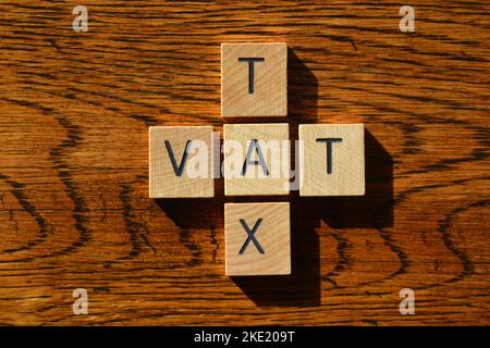 VAT, Akronym für Value Added Tax and Tax, Wort in Holzbuchstaben isoliert auf texturiertem Holzhintergrund Stockfoto