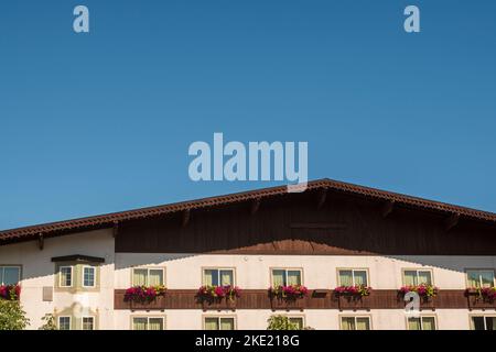 Eine minimalistische Komposition eines bayrisch-syle-Hotels mit bunten Blumenkästen und blauem Himmel in der deutschen Stadt Leavenworth, Washington, USA. Stockfoto