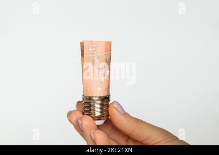 Eine Frauenhand hält eine Patrone aus einer Glühbirne mit Euro auf weißem Hintergrund, der Preis für Strom, Technologie Stockfoto