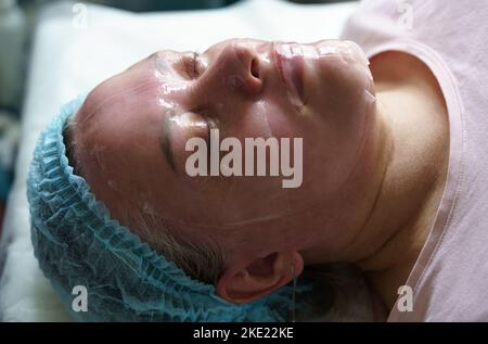 Nahaufnahme einer schönen Frau mit geschlossenen Augen und einer kosmetischen Maske auf der Gesichtshaut. Blick von oben. Verjüngungskonzept Stockfoto