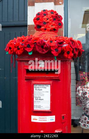 Bagshot, Surrey, Großbritannien. 7.. November 2022. Eine lebendige Erinnerungsdarstellung mit gestrickten Mohnblumen auf einer Royal Mail-Briefbox in der Bagshot High Street, in Erinnerung an die Menschen, die ihr Leben für unsere Freiheit hingegeben haben. Quelle: Maureen McLean/Alamy Stockfoto
