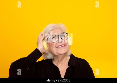 Lächelnde ältere Frau mit Kopfhörern, die Musik hört Stockfoto