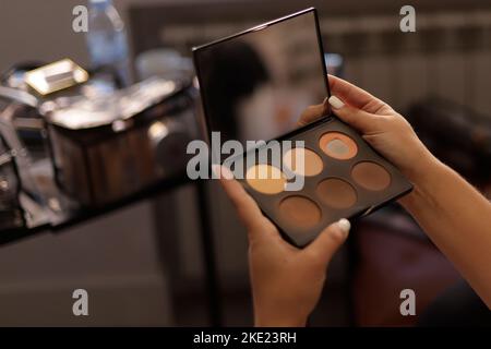 latina Frauen Hände halten Make-up Palette mit Spiegel drinnen Stockfoto