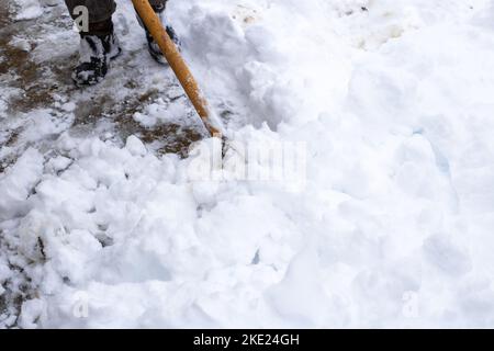 Ein Mann reinigt den Schnee im Hof mit einer Schaufel. Winterschneewehen. Stockfoto