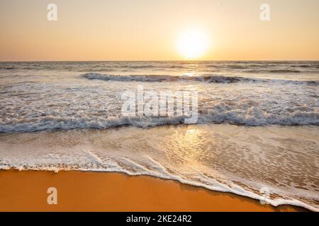 Wunderschöner Strand in den südlichen Staaten von Karnataka (oder Goa oder Kerala) mit Sonnendach und 2 Liegestühlen, Februar und März. Gelber Sonnenuntergang Stockfoto