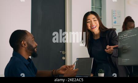 Systemingenieure feiern erfolgreiche Codeentwicklung und führen highfive-Gesten mit dem Coder durch. Team von IT-Entwicklern, die den Algorithmus nach erfolgreichem Erreichen des Datenbankservers analysieren. Handgeführte Aufnahme. Stockfoto