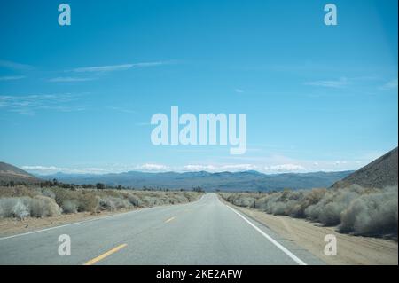 Fahrt auf dem Highway 178 in der kalifornischen Mojave-Wüste mit der Sierra Nevada Mountain Range im Horizont Stockfoto
