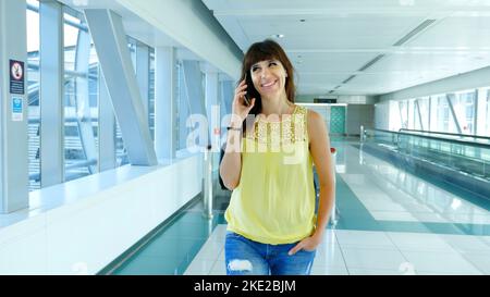 Frau, die auf dem Automatic Walkway steht, in der U-Bahnüberfahrt, spricht, ihr Telefon benutzt, ein Mittel der Kommunikation, Gadget. Das Konzept ist immer in Kontakt. Hochwertige Fotos Stockfoto