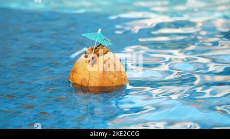 Frischer Kokosnusssaft-Cocktail mit Trinkhalm, der in einem erfrischenden blauen Swimmingpool schwimmt. Hochwertige Fotos Stockfoto