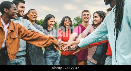 Fröhliches Team von multiethnischen jungen Menschen, die sich zusammenschließen - Vielfalt, Einheit, Vertrauen, Einheit, internationales Jugendkulturkonzept - interracial Stockfoto