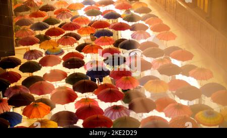 Die Dubai Mall spiegelt die Schaufenster wider und bietet Dutzende von offenen mehrfarbigen Regenschirmen, die in Form einer improvisierten Decke aufgehängt sind. Hochwertige Fotos Stockfoto