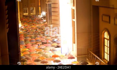 Die Dubai Mall spiegelt die Schaufenster wider und bietet Dutzende von offenen mehrfarbigen Regenschirmen, die in Form einer improvisierten Decke aufgehängt sind. Hochwertige Fotos Stockfoto