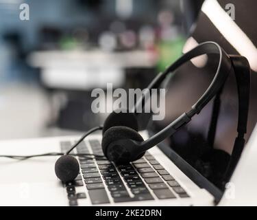 Headset auf einer Laptop-Tastatur in einem leeren Büro. Stockfoto