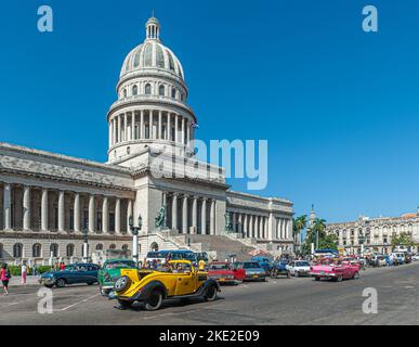 Kapitolgebäude in Havanna, Kuba, an dem alte amerikanische Autos vorbeifahren Stockfoto