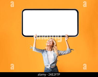 Junge Glückliche Blonde Frau Hält Großes Unbeschriftete Smartphone Über Dem Kopf Stockfoto