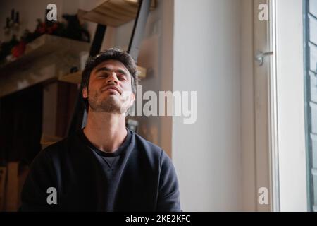 Junger Mann in der Meditation sitzt mit geschlossenen Augen und Kopf nach hinten gebogen. Stockfoto