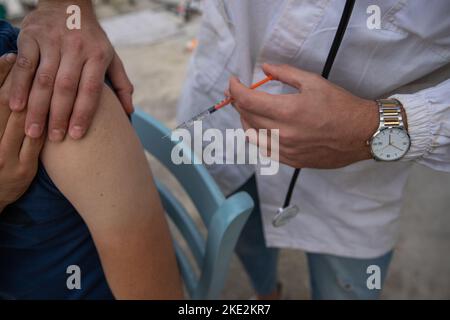 Arzt, der den Arm des Patienten hält, um ihm die Injektion zu verabreichen. Impfstoffsitzung. Stockfoto