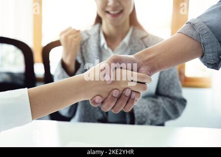 Unternehmensfusion, asiatische Geschäftsleute schütteln die Hände im Konferenzraum und zeigen ihre Zusammenarbeit, um ihre Marketing-Bemühungen zu stärken Stockfoto