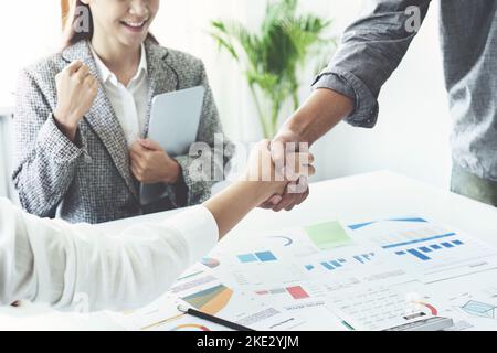 Unternehmensfusion, asiatische Geschäftsleute schütteln die Hände im Konferenzraum und zeigen ihre Zusammenarbeit, um ihre Marketing-Bemühungen zu stärken Stockfoto