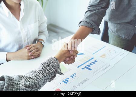 Unternehmensfusion, asiatische Geschäftsleute schütteln die Hände im Konferenzraum und zeigen ihre Zusammenarbeit, um ihre Marketing-Bemühungen zu stärken Stockfoto