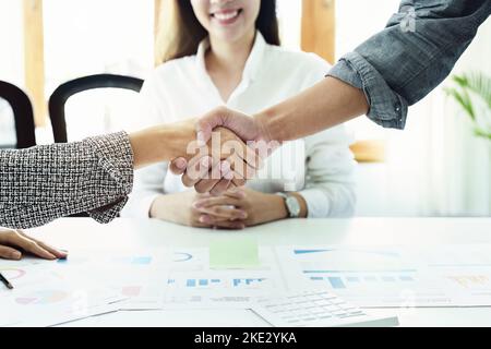 Unternehmensfusion, asiatische Geschäftsleute schütteln die Hände im Konferenzraum und zeigen ihre Zusammenarbeit, um ihre Marketing-Bemühungen zu stärken Stockfoto