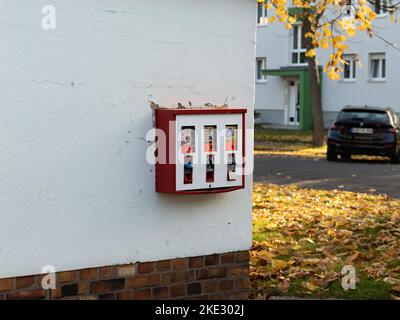 Roter Kaugummi-Automaten an einer Wand in einem Wohnviertel. Süßigkeiten und billiges Spielzeug für Kinder. Die Vintage-Maschine arbeitet mit Euro-Münzen. Stockfoto