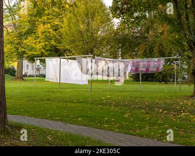 Wäsche hängt an einer Wäscheleine in einem Hinterhof. Bettwäsche und Decken trocknen im Freien im Wind. Housekeeping in einem Wohnviertel. Stockfoto