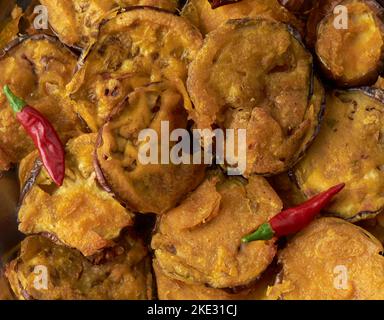 Nahaufnahme von gebratener Aubergine mit Teig und roten Chilli, goldbraun knusprig vegetarisches Vollformat-Food-Hintergrund direkt von oben aufgenommen Stockfoto
