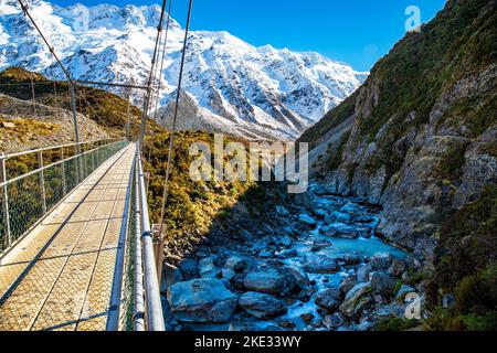 Überqueren Sie das Hooker Valley auf einer leeren Schaukelbrücke auf dem Weg durch das Hooker Valley, um den Blick auf Aoraki am Hooker Lake zu genießen Stockfoto