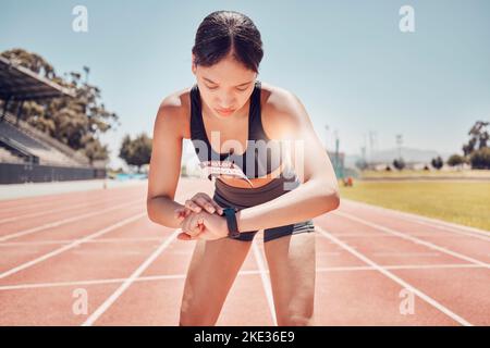 Fitness, Smartwatch oder Läuferin checken digitale App für Training, Marathon oder Training auf der Sportstadionstrecke. Gesundheit oder schwarze Frau mit Stockfoto