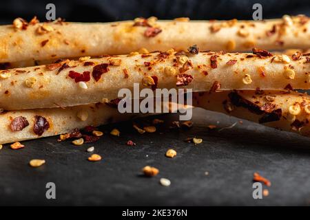 Grissini mit Chili Flakes, auch bekannt als Brotstangen, grissino oder Dipping Sticks, sind in der Regel Bleistift-große Sticks aus knackigem, trocken gebackenem Brot origi Stockfoto