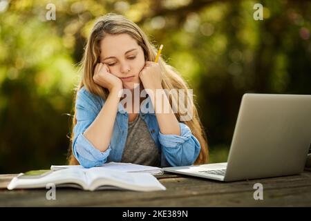 Ich bin darüber. Eine junge Frau, die erschöpft aussieht, während sie draußen studiert. Stockfoto