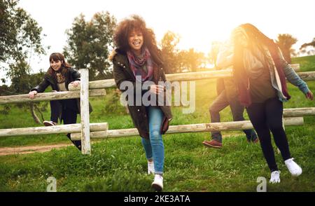 Wir wollen nur eine Gruppe von Freunden Viel Spaß. springen über einen Zaun in einem Feld zum Spaß. Stockfoto