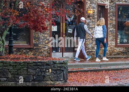 Ein Paar schlendert an einem nebligen Herbstmorgen in Highlands, North Carolina, entlang der Main Street. (USA) Stockfoto