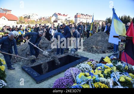 Lviv, Ukraine. 09.. November 2022. Bestatter begraben den Sarg des ukrainischen Soldaten Taras Havrylyshyn, der infolge der russischen Militärinvasion in die Ukraine starb, während seiner Beerdigung auf dem Lytschakiv-Friedhof in Lemberg. In Lemberg fand die Beerdigung von Taras Havrylyshyn, einem Soldaten der Artilleriebrigade 45. der ukrainischen Streitkräfte, statt. Er starb, als er ukrainische Länder von den russischen Invasoren in südlicher Richtung befreite. Taras Havrylyshyn war ein bekanntes Mitglied der ukrainischen Pfadfinderorganisation "Plast". Kredit: SOPA Images Limited/Alamy Live Nachrichten Stockfoto