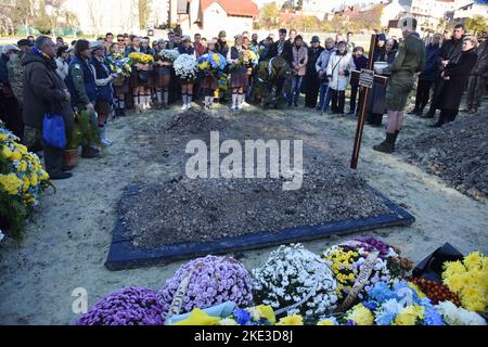 Lviv, Ukraine. 09.. November 2022. Auf dem Lytschakiv-Friedhof in Lemberg stehen Menschen in der Nähe des Grabes des ukrainischen Soldaten Taras Havrylyschyn, der infolge der russischen Militärinvasion in die Ukraine gestorben ist. In Lemberg fand die Beerdigung von Taras Havrylyshyn, einem Soldaten der Artilleriebrigade 45. der ukrainischen Streitkräfte, statt. Er starb, als er ukrainische Länder von den russischen Invasoren in südlicher Richtung befreite. Taras Havrylyshyn war ein bekanntes Mitglied der ukrainischen Pfadfinderorganisation "Plast". Kredit: SOPA Images Limited/Alamy Live Nachrichten Stockfoto