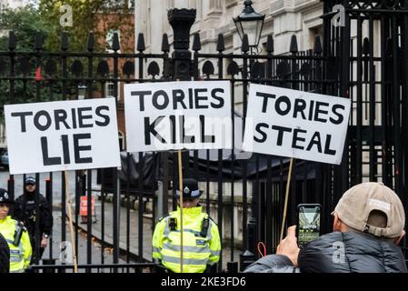 Beleidigende regierungsfeindliche Plakate vor der Downing Street bei Protesten in London, Großbritannien. Person, die auf dem Mobiltelefon fotografiert. Tories lügen, töten, stehlen Stockfoto