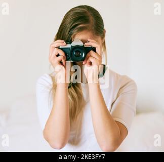 Sagen Sie Käse. Eine nicht erkennbare junge Frau, die zu Hause mit ihrer Kamera ein Foto gemacht hat. Stockfoto