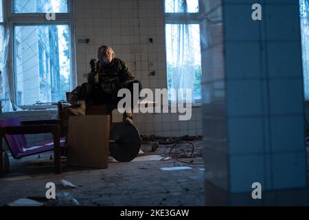 Post-Apokalypse. Eine junge Frau sitzt und raucht in einem verlassenen Gebäude. Konzept eines Mannes, der in einer post-apokalyptischen Welt auf der Suche nach Nahrung wandert. Stockfoto