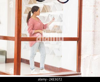 Einkaufen, Einzelhandel und Frau mit Brille in einem Geschäft für hochwertige Auswahl, Rahmen für Werbung und Augenpflege. Entscheidung, Mädchen oder Kunde Optionen überprüfen Stockfoto