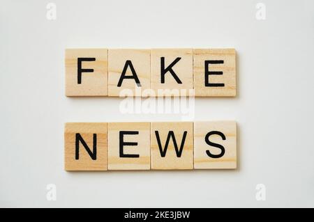 Fake News. Schwarzer Schriftzug auf Holztellern. Weißer Hintergrund. Stockfoto