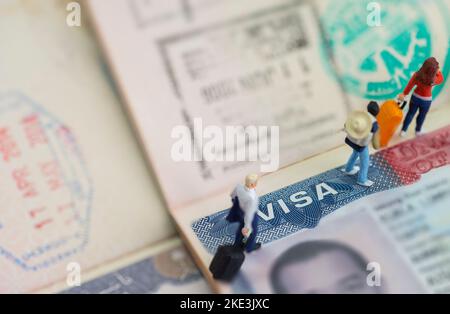 Mini-Spielzeug Studio eingerichtet - Expatriate Geschäftsmann und andere Reisende reisen mit Visum auf Reisepass als Hintergrund. Stockfoto