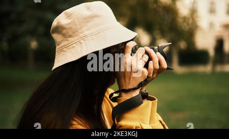 Ein Mädchen im Park hält eine Kamera in den Händen und macht ein Foto Stockfoto