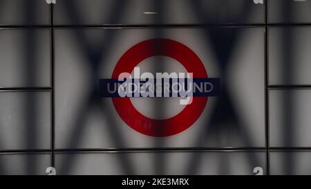 Ein Schild für die Londoner U-Bahn, das während eines Streiks von Mitgliedern der Rail, Maritime and Transport Union (RMT) und Unite durch die geschlossenen Fensterläden am Bahnhof Euston im Zentrum von London in einem lang andauern Streit um Arbeitsplätze und Renten gesehen wird. Der Streik der Verkehrsarbeiter in London wird voraussichtlich ein Reisechaos mit begrenzten Diensten auf der Tube verursachen. Bilddatum: Donnerstag, 10. November 2022. Stockfoto