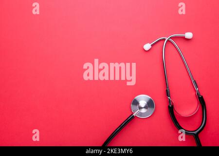 Medizinisches Stethoskop auf rotem Hintergrund. Gesund Stockfoto